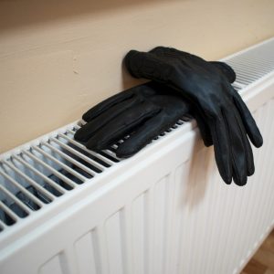 Black winter gloves on a heater.